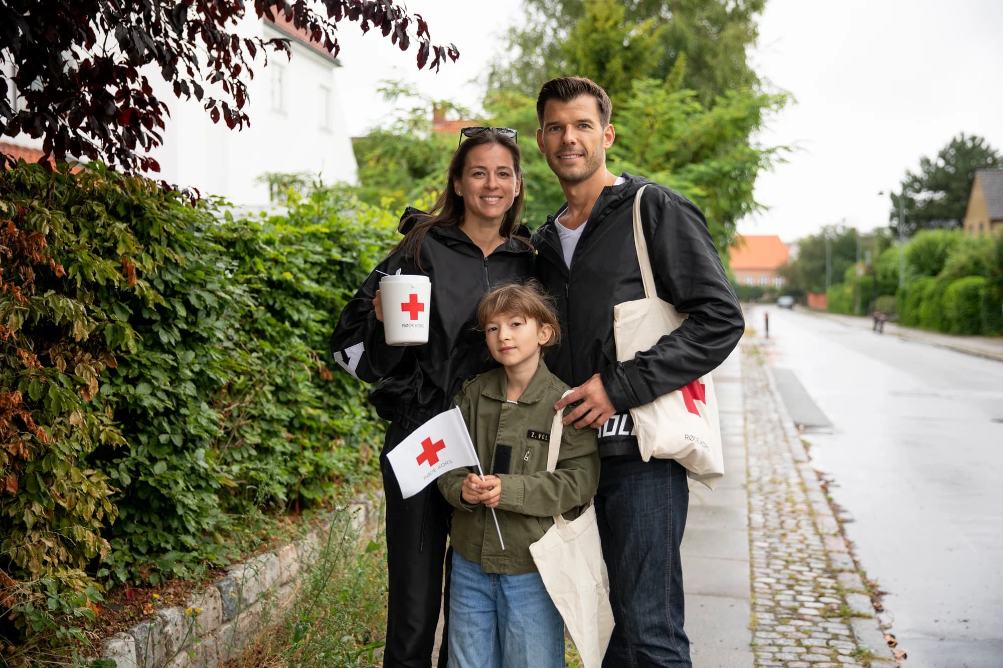 A family collecting donations for Danish Red Cross on a residential street.