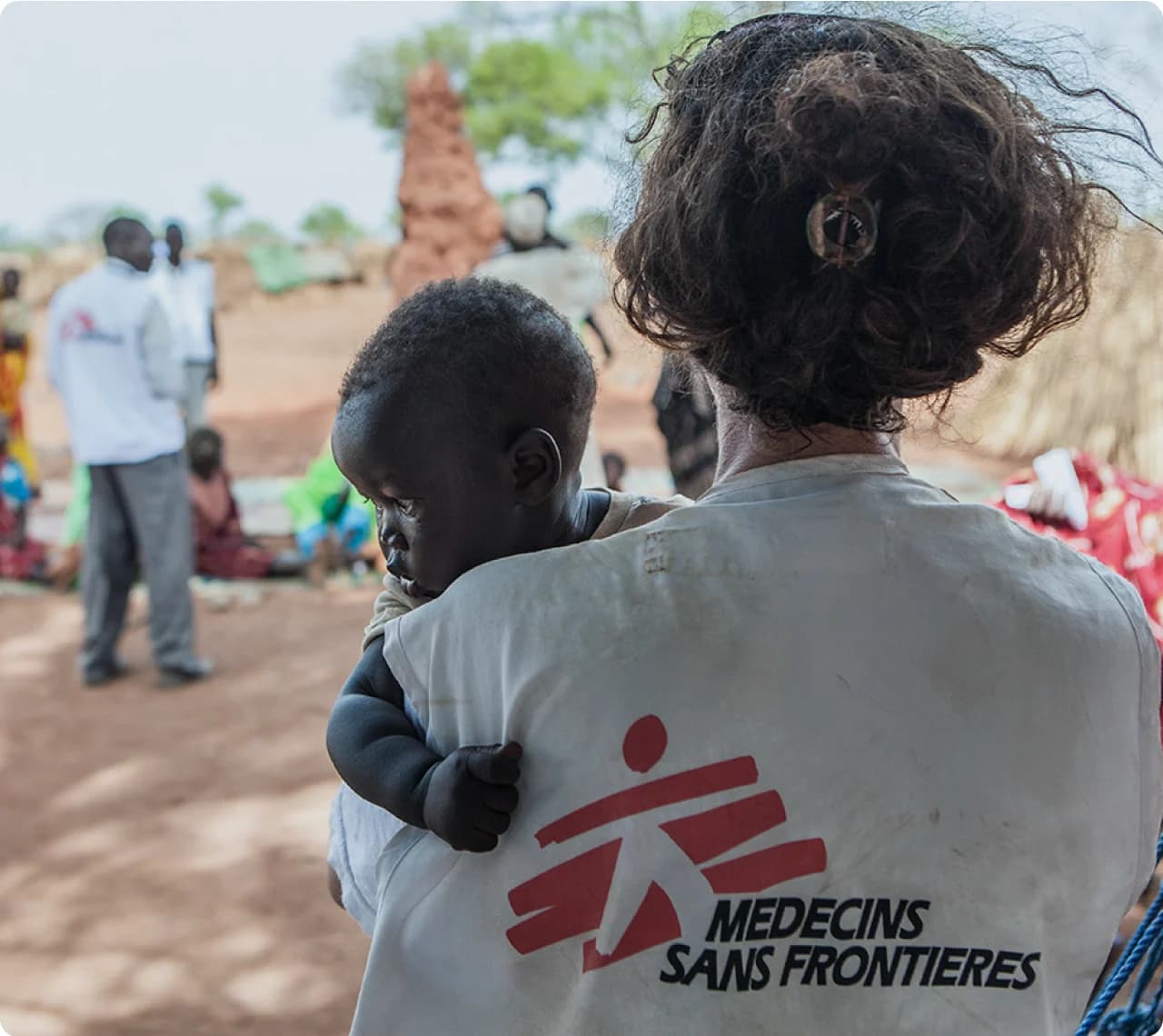 A Médecins Sans Frontières team member holding a child in the field.