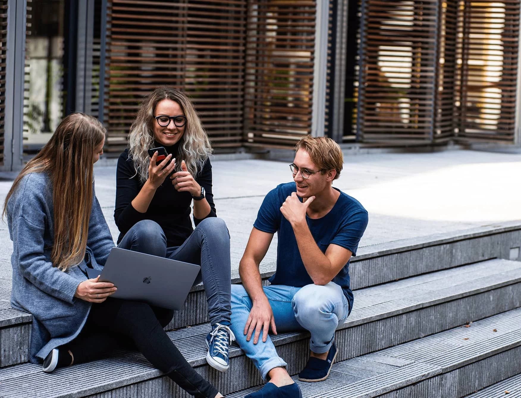 Three students talking together on outdoor steps.