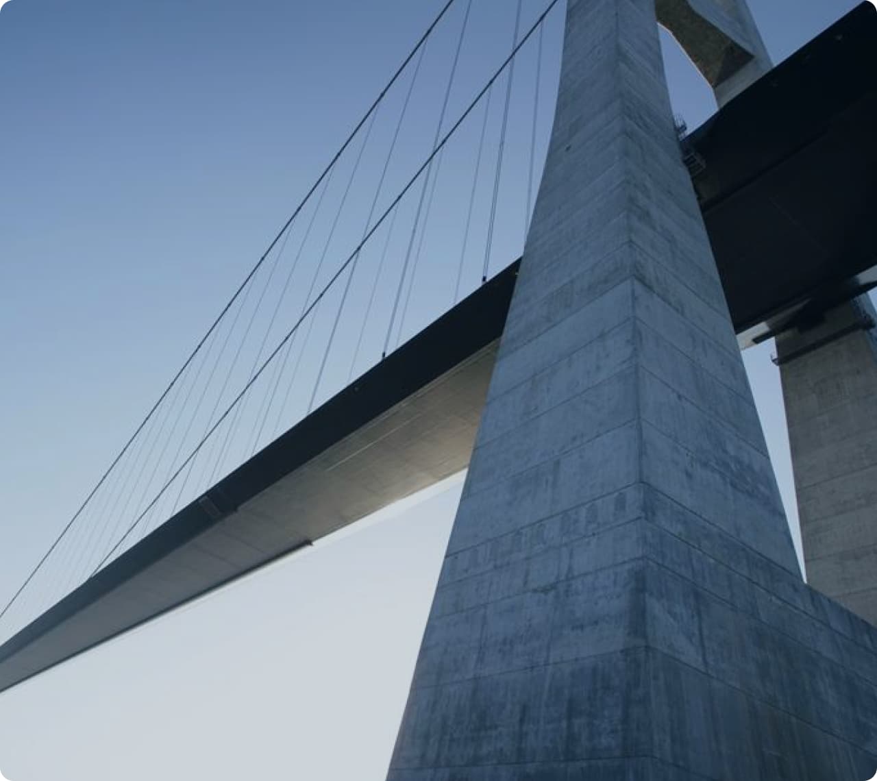 The concrete structure and cables of a suspension bridge seen from below.