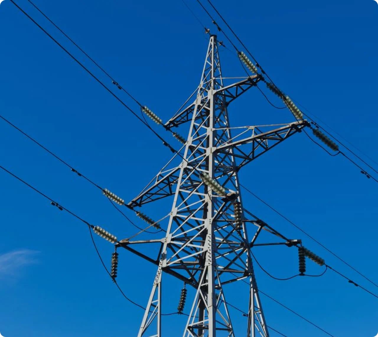 Electricity transmission tower against a clear blue sky.