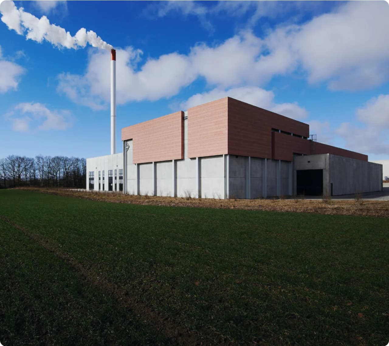Energy facility with a tall chimney under a blue sky.