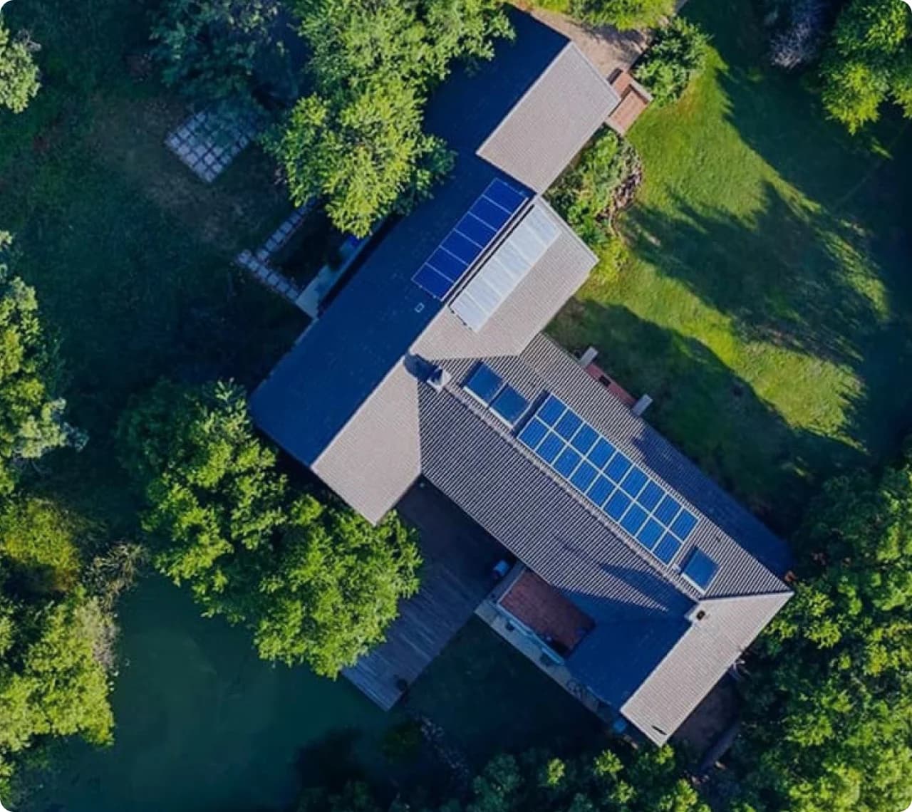 Aerial view of a home with solar panels surrounded by trees.
