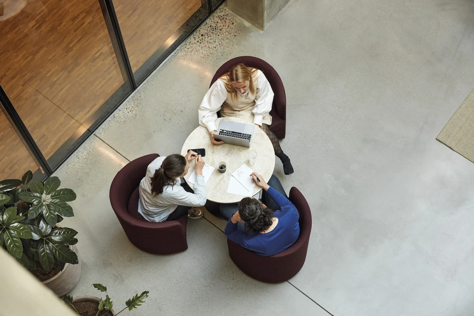 Three e-conomic colleagues working around a small table, photographed from above.