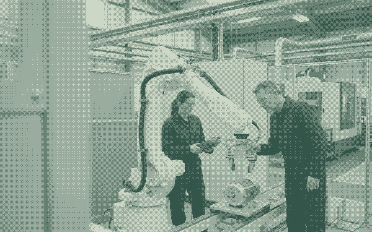 Illustrative scene of two engineers checking robot tooling in an automated manufacturing cell.
